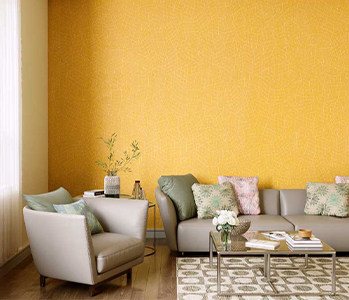 A living room with orange wall, grey sofa set and a coffee table